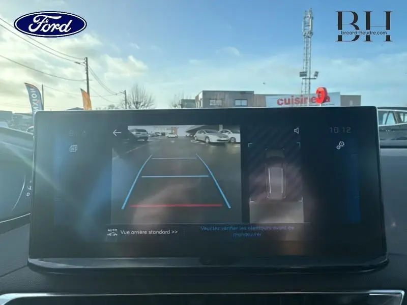 Vue de l'écran tactile intérieur du Peugeot 5008 blanc, affichant la caméra de recul avec lignes de guidage.