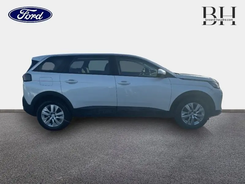 Profil droit d'un Peugeot 5008 blanc Banquise avec jantes alu et barres de toit visibles sur fond neutre.