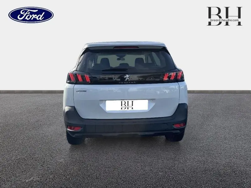 Vue arrière d'un Peugeot 5008 blanc Banquise avec feux arrière à griffes rouges et bande noire brillante.