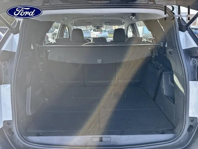Coffre ouvert vu de l'arrière d'un Peugeot 5008 blanc Banquise, montrant l'espace de chargement et les sièges arrière.