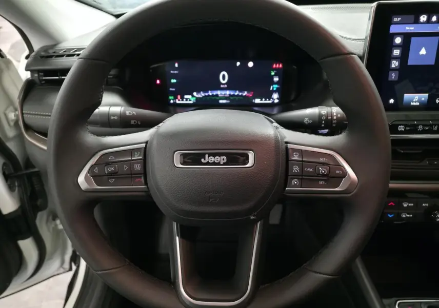 Vue rapprochée du volant Jeep Compass 2024 noir avec tableau de bord numérique et écran tactile central visible.