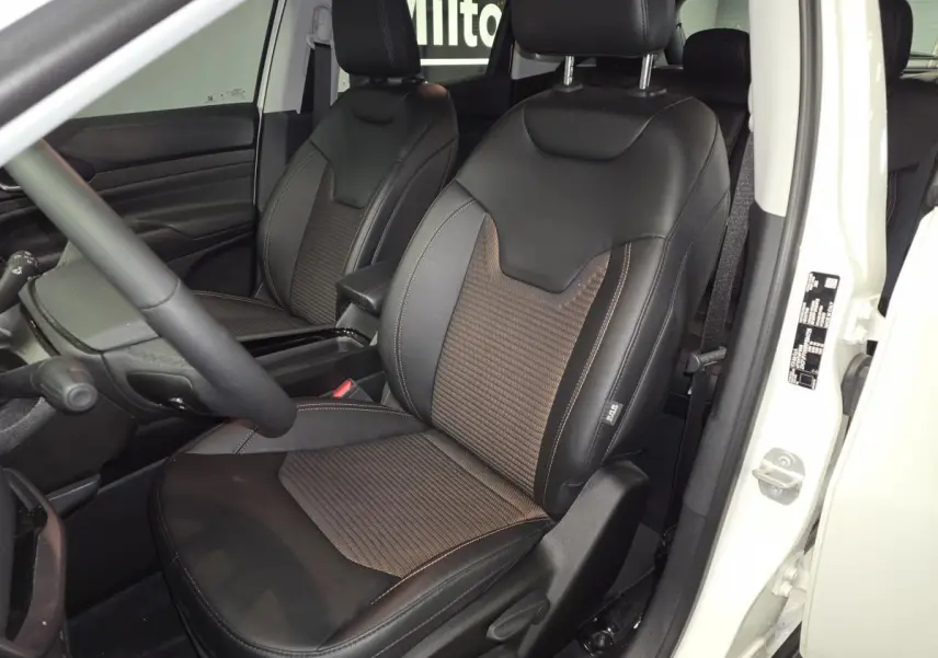 Vue intérieure côté conducteur du Jeep Compass 2024 blanc, sièges avant en sellerie mixte noir et bronze.