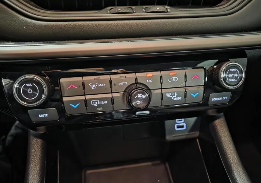 Gros plan sur la console centrale noire du Jeep Compass 2024, montrant les commandes de climatisation et audio.