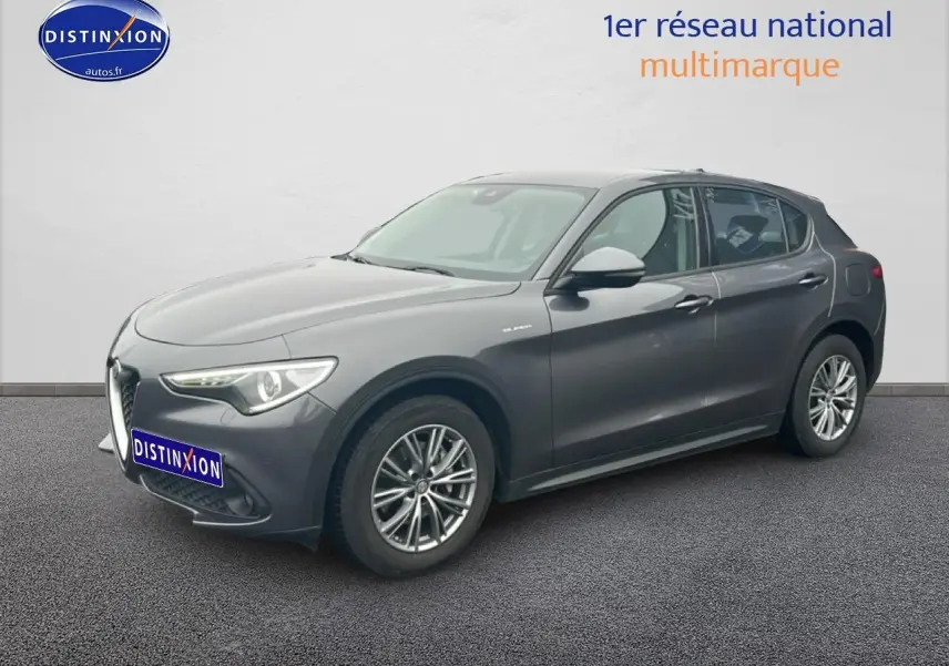 Vue 3/4 avant droit d'une Alfa Romeo Stelvio gris vesuvio metal avec jantes alu et feux LED.