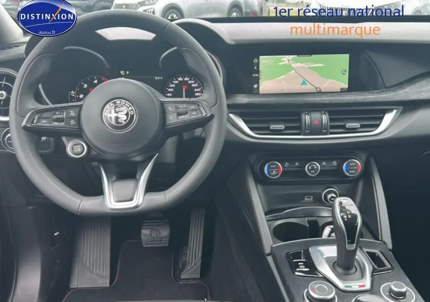 Vue intérieure de l'Alfa Romeo Stelvio 2021, tableau de bord et console centrale avec écran tactile et volant cuir.