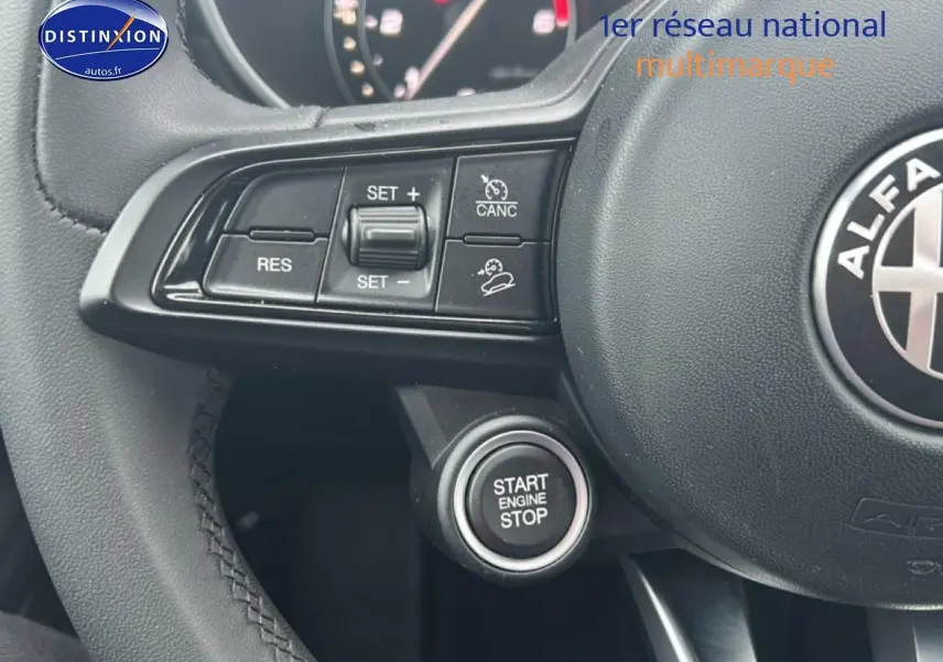 Gros plan sur le volant cuir noir d'Alfa Romeo Stelvio avec commandes de régulateur et bouton start/stop visible.