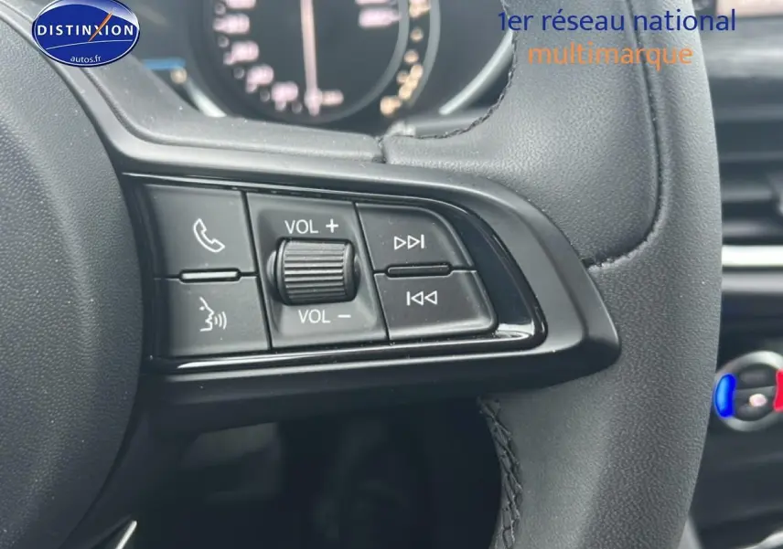 Gros plan sur les commandes audio au volant cuir noir de l'Alfa Romeo Stelvio gris Vesuvio metal, intérieur moderne.