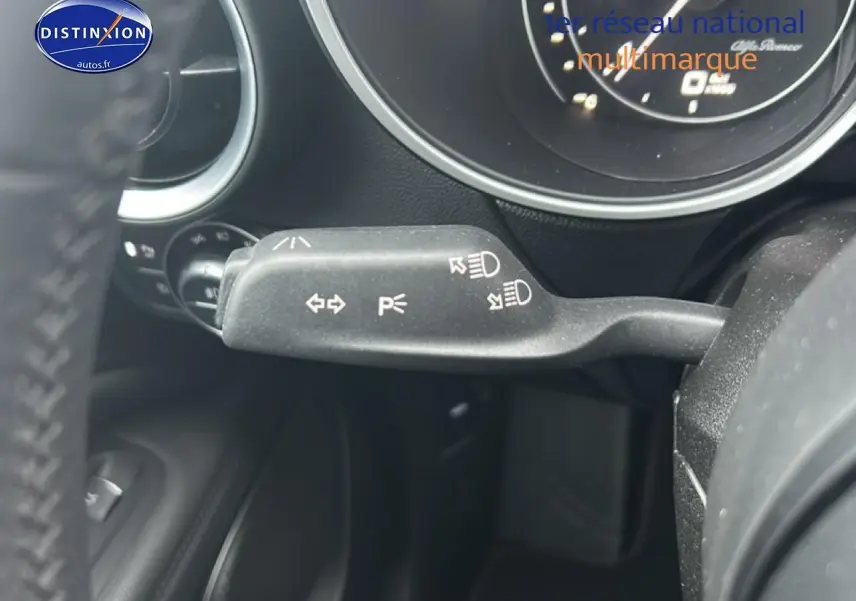 Gros plan sur la commande de clignotants et feux à gauche du volant d'Alfa Romeo Stelvio gris Vesuvio metal.