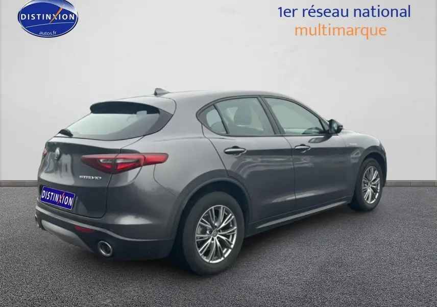 Vue 3/4 arrière droite d'un Alfa Romeo Stelvio gris Vesuvio metal avec jantes alu et feux arrière LED.