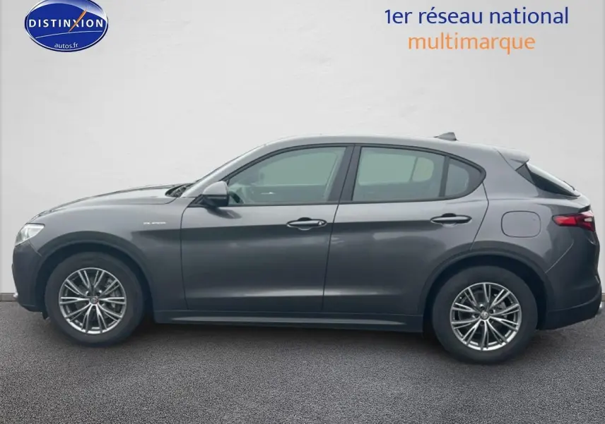 Profil droit d'un Alfa Romeo Stelvio gris vesuvio metal, mettant en valeur ses jantes alliage et lignes fluides.