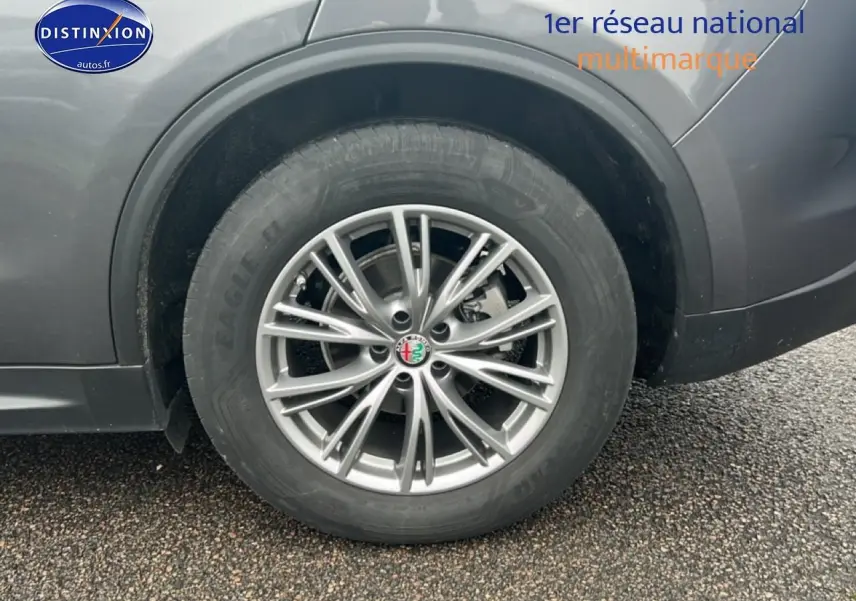 Gros plan sur la roue arrière droite avec jante alu argentée de l'Alfa Romeo Stelvio gris Vesuvio metal.
