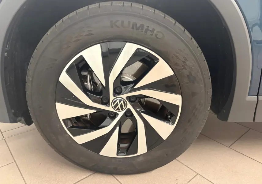 Gros plan sur la roue avant droite du Volkswagen Tiguan 1.5 eHybrid Nightshade Blue avec jante alliage bicolore.