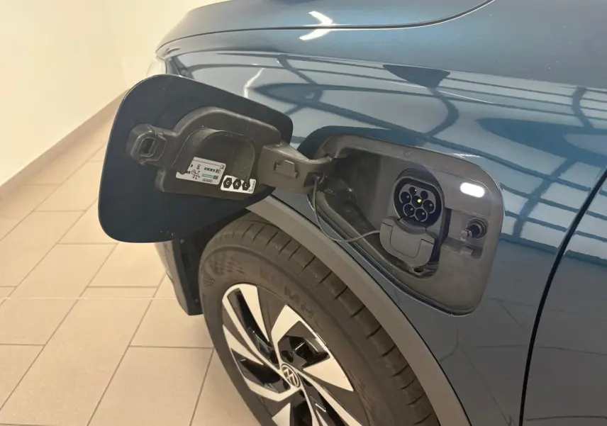 Prise de recharge ouverte côté gauche sur Volkswagen Tiguan 1.5 eHybrid TSI 204 Nightshade Blue, vue rapprochée sur la roue et la carrosserie.