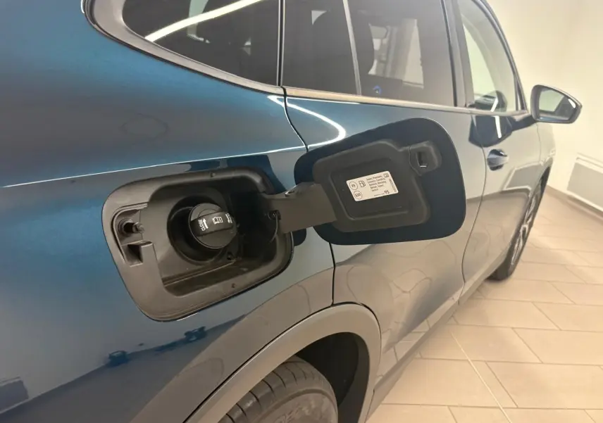 Vue côté gauche arrière du Volkswagen Tiguan 1.5 eHybrid en bleu Nightshade, trappe de recharge ouverte visible.