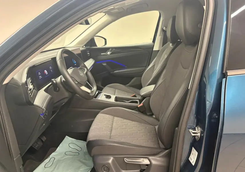 Vue intérieure côté conducteur du Volkswagen Tiguan 2025 en Nightshade Blue, sièges et volant chauffants visibles.