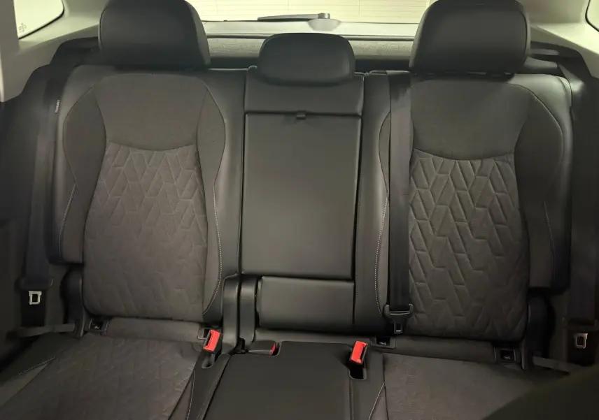 Vue intérieure des sièges arrière du Volkswagen Tiguan 2025, tissu noir avec motifs géométriques et ceinture de sécurité visible.