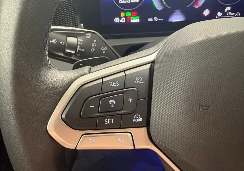 Gros plan sur le côté gauche du volant du Volkswagen Tiguan 2025, montrant les commandes de régulateur de vitesse et l'affichage numérique en arrière-plan.