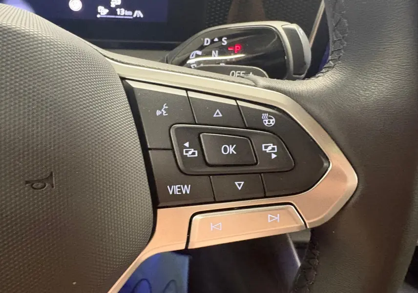Gros plan sur le volant côté gauche du Volkswagen Tiguan 2025, avec commandes intégrées et indication de siège chauffant.