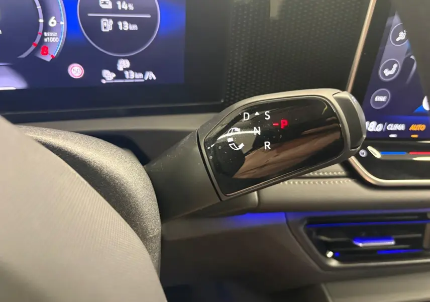 Gros plan sur le levier de vitesses automatique du Volkswagen Tiguan 1.5 eHybrid, avec tableau de bord numérique en arrière-plan.