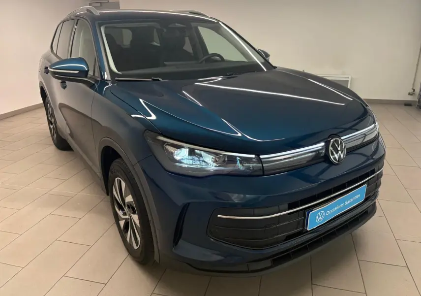 Volkswagen Tiguan 1.5 eHybrid en Nightshade Blue, vue 3/4 avant droit, intérieur visible, éclairage LED allumé.