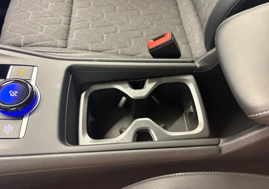 Gros plan sur la console centrale du Volkswagen Tiguan 2025, avec porte-gobelets et bouton rotatif bleu Nightshade Blue.