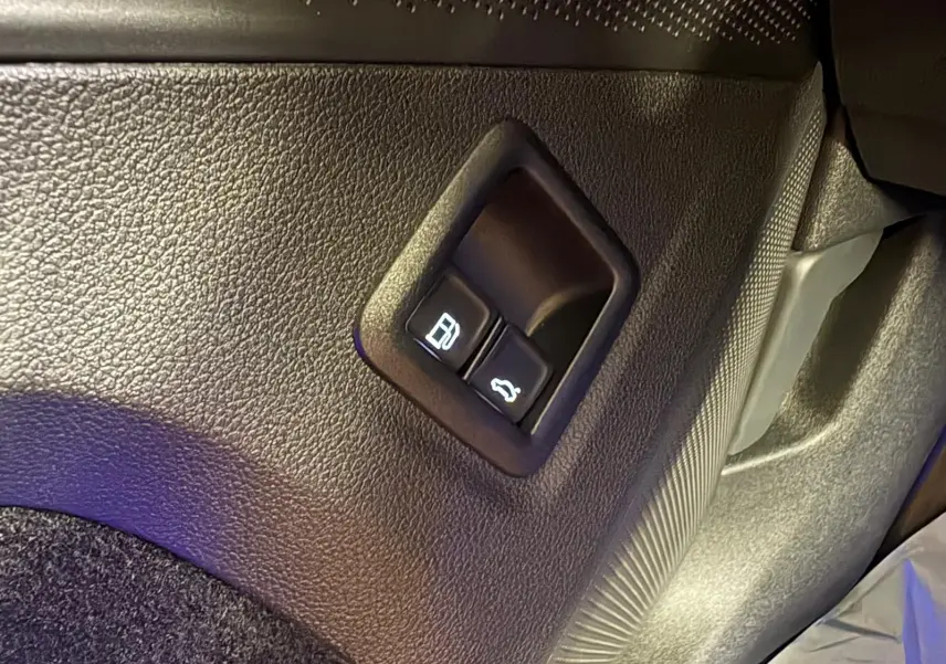 Gros plan sur les boutons d'ouverture du réservoir et du coffre dans l'habitacle du Volkswagen Tiguan Nightshade Blue 2025.