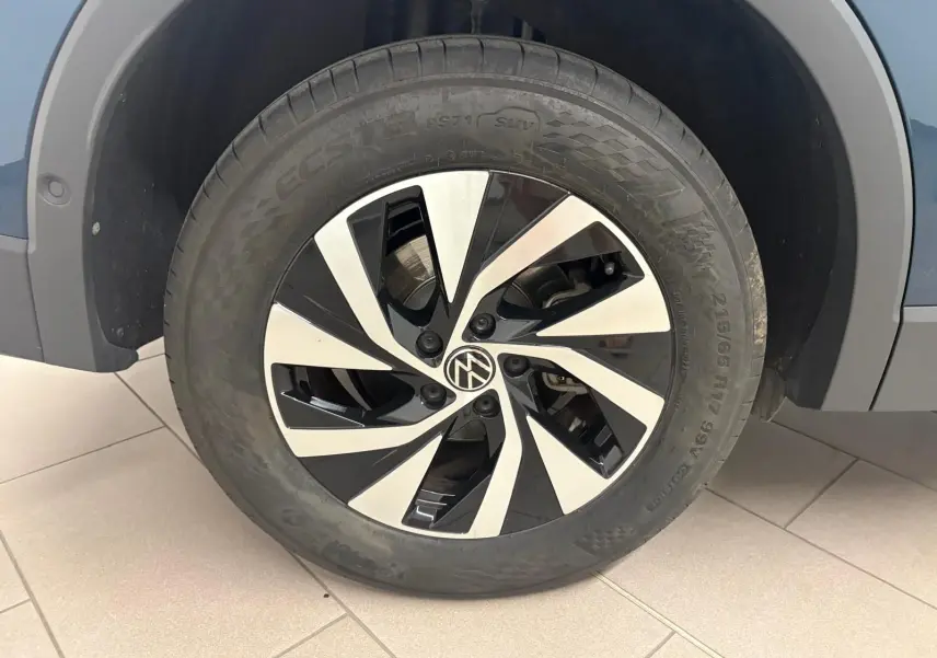 Gros plan sur la roue avant droite du Volkswagen Tiguan 1.5 eHybrid en Nightshade Blue avec jante alliage bicolore.
