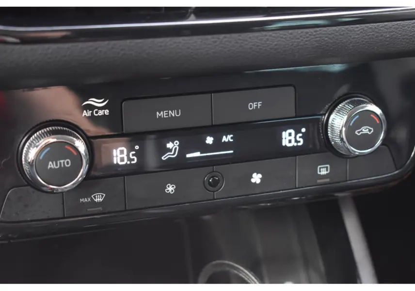 Gros plan sur la commande de climatisation automatique bi-zone noire avec affichage digital à 18,5°C dans une Skoda Scala blanche.