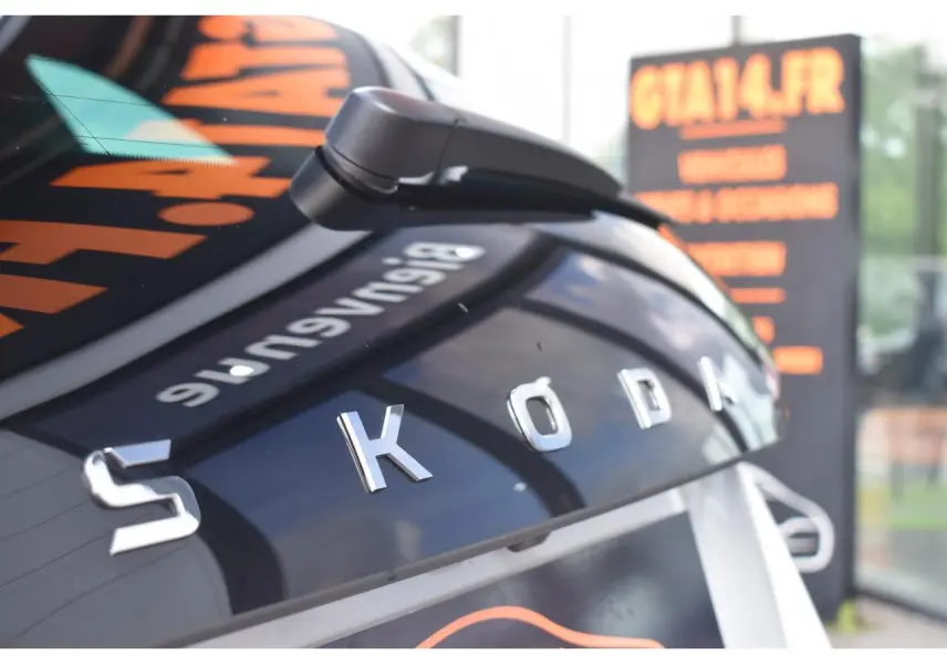 Gros plan sur l'arrière noir brillant d'une Skoda Scala blanche, mettant en valeur le logo chromé SKODA.