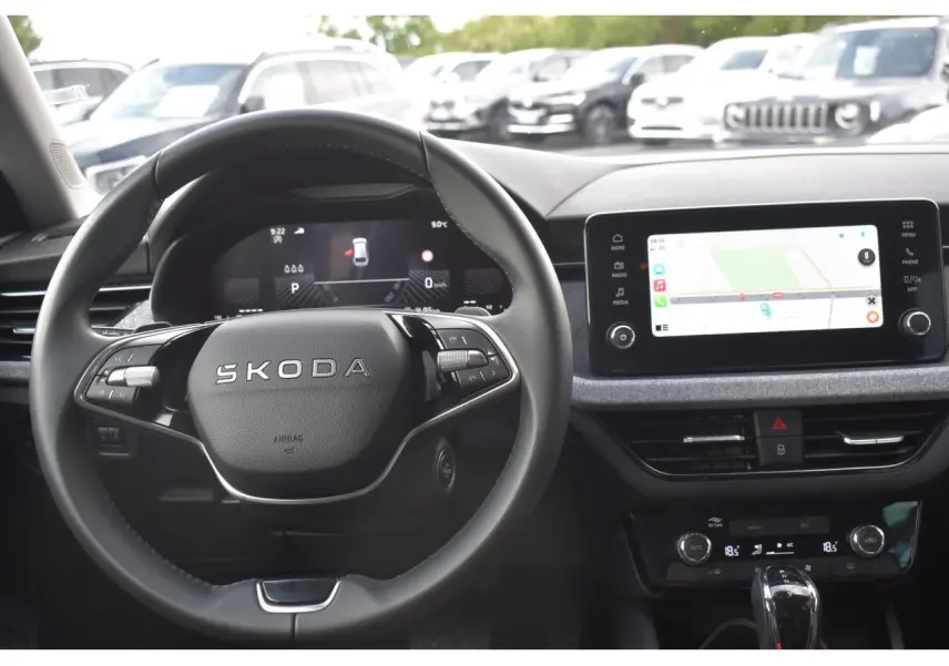Vue intérieure centrée sur le volant SKODA et l'écran tactile du tableau de bord du SCALA blanc glacier 2025.