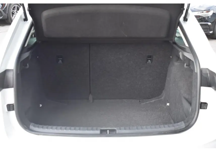 Coffre ouvert vu de l'arrière d'une Skoda Scala blanc glacier, montrant l'espace de chargement vide et doublé de tissu noir.