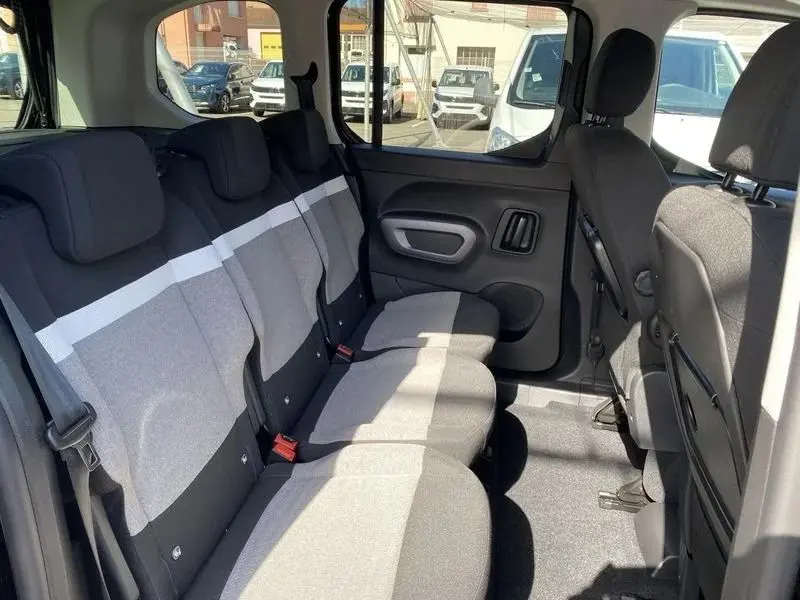 Vue intérieure du Citroën Berlingo 2025 montrant la banquette arrière en tissu gris clair avec bande blanche, côté droit.