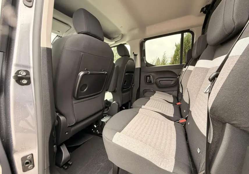 Vue intérieure côté droit du Citroën Berlingo 2025 gris Artense, montrant la banquette arrière trois places et les dossiers avant.