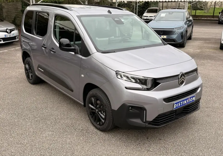 Vue 3/4 avant droit du Citroën Berlingo gris Artense 2025 avec jantes noires et calandre moderne sur parking.