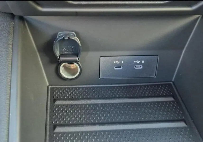 Prise allume-cigare et double port USB-C visibles dans le compartiment avant du Renault Captur E-Tech hybride gris Rafale.