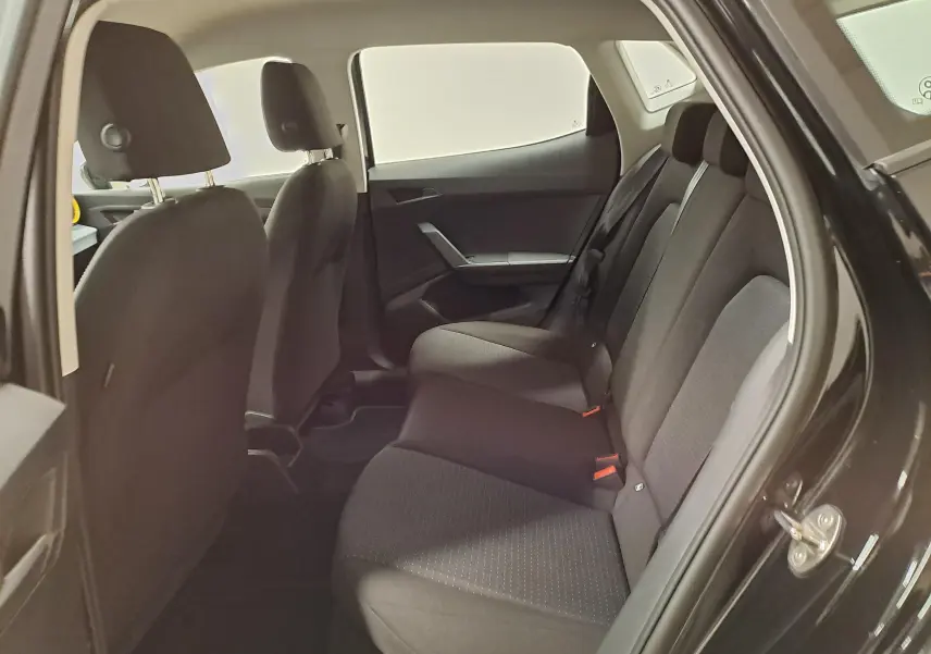 Vue intérieure côté droit des sièges arrière noirs du SEAT Ibiza 2024, version 1.0 TSI STYLE, avec ceintures rouges visibles.