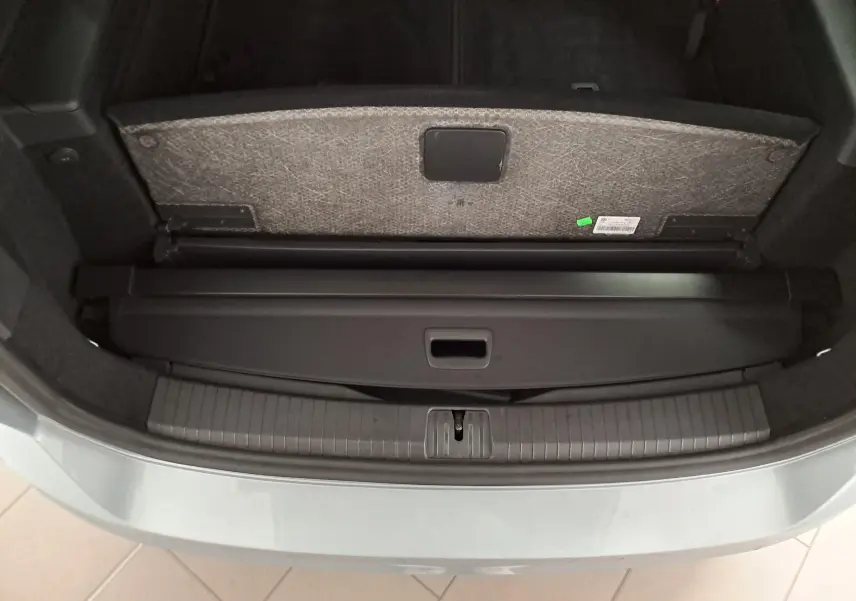 Coffre ouvert vu de dessus d’un Volkswagen Touran 2025 en Argent Dolomite avec cache-bagages et seuil de coffre visible.