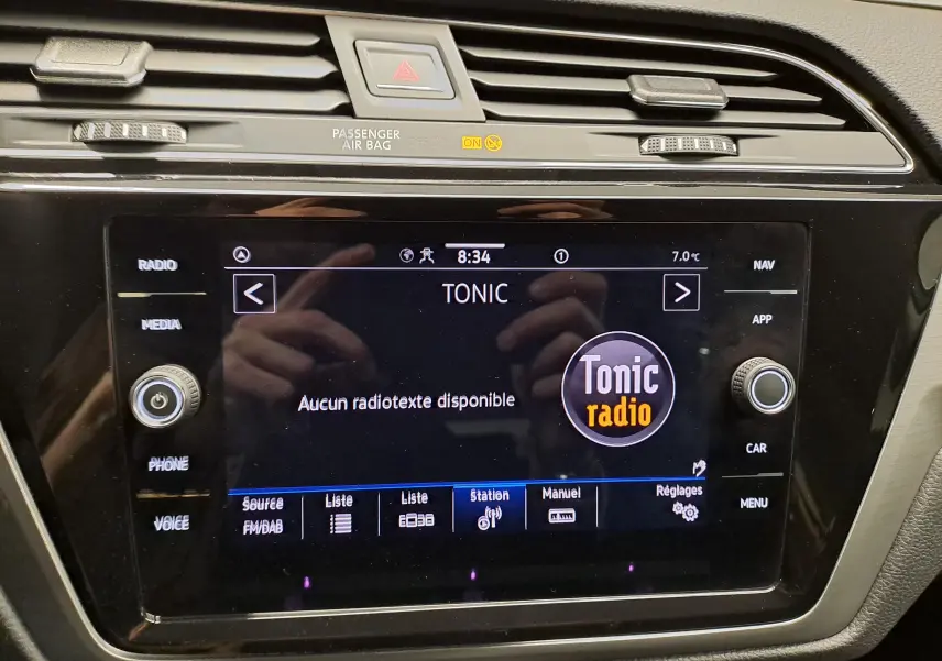 Écran tactile central du Volkswagen Touran 2025 affichant la radio Tonic, entouré de commandes noires et grises.