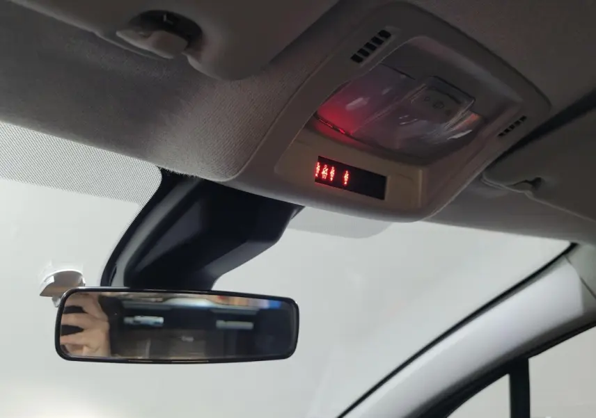 Vue intérieure du plafond de la Citroën C3 beige 2022, avec rétroviseur central et éclairage de toit rouge allumé.