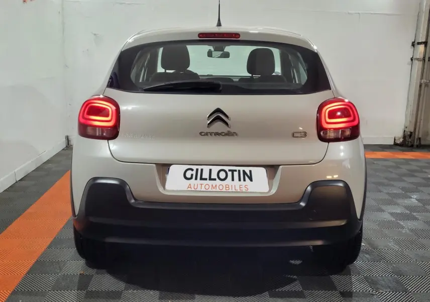 Vue arrière d'une Citroën C3 beige 2022 avec feux arrière allumés dans un garage intérieur.