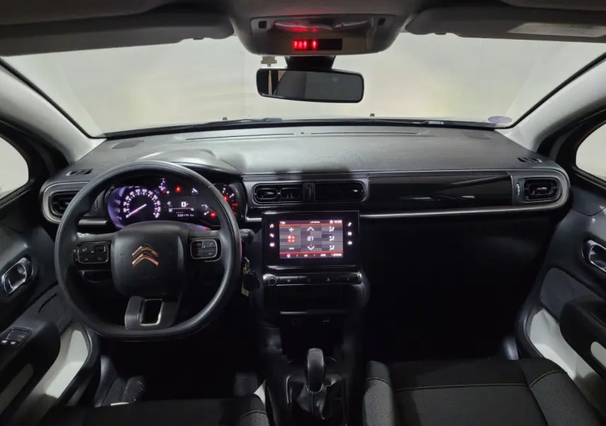 Vue intérieure avant de la Citroën C3 beige 2022, tableau de bord noir avec écran tactile central et volant multifonctions.
