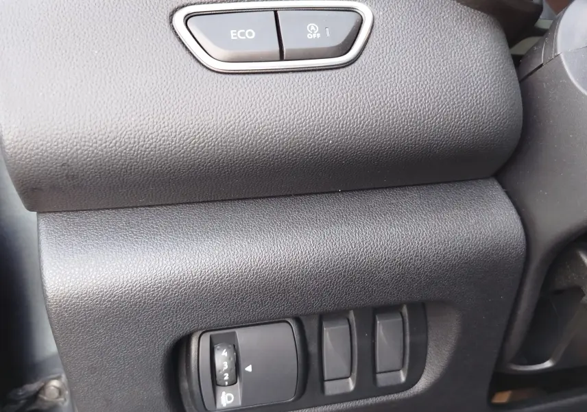 Détail intérieur du tableau de bord côté conducteur du Renault Kadjar 2021, boutons ECO et réglage des phares visibles.