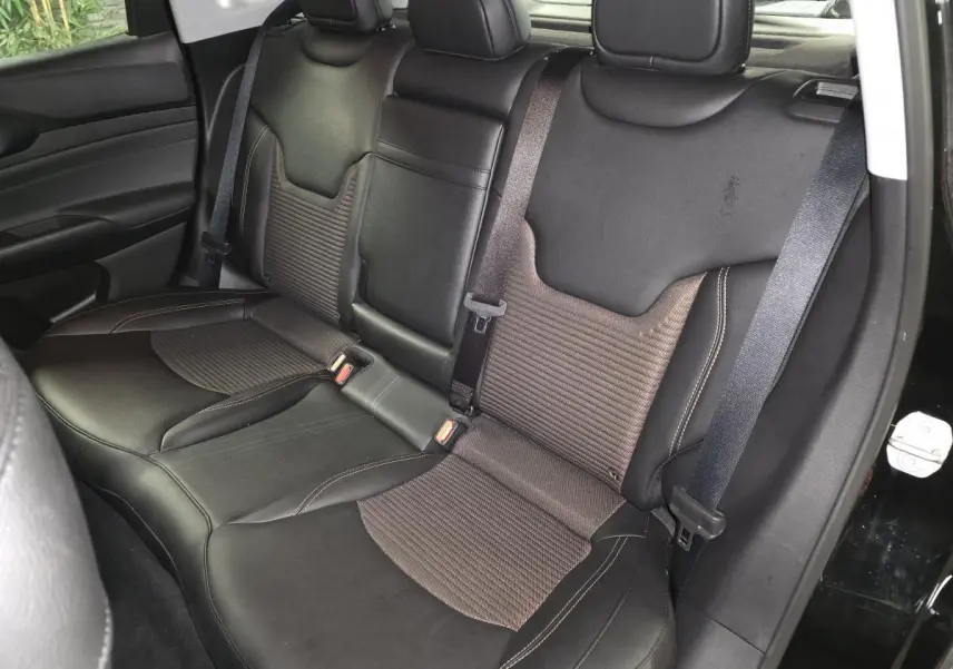 Vue intérieure côté arrière droit montrant la banquette mixte tissu/TEP noire et bronze du Jeep Compass 2024.