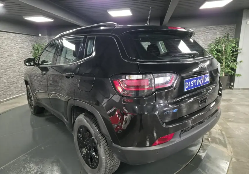 Vue 3/4 arrière droite du Jeep Compass noir brillant avec jantes noires et feux arrière LED en intérieur showroom.