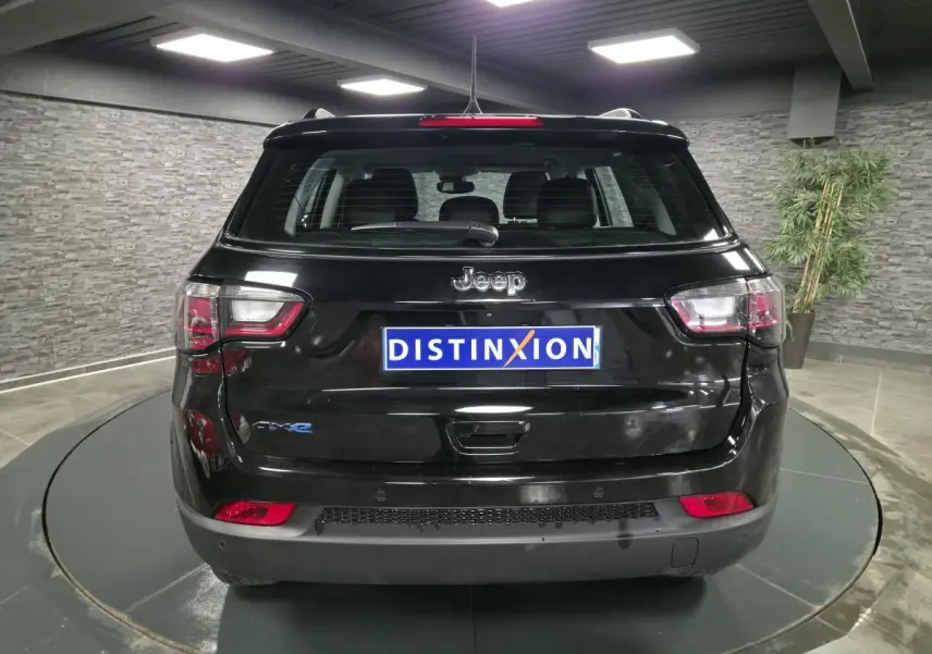 Vue arrière d'un Jeep Compass noir 2024 avec logo 4xe et feux arrière LED dans un showroom.