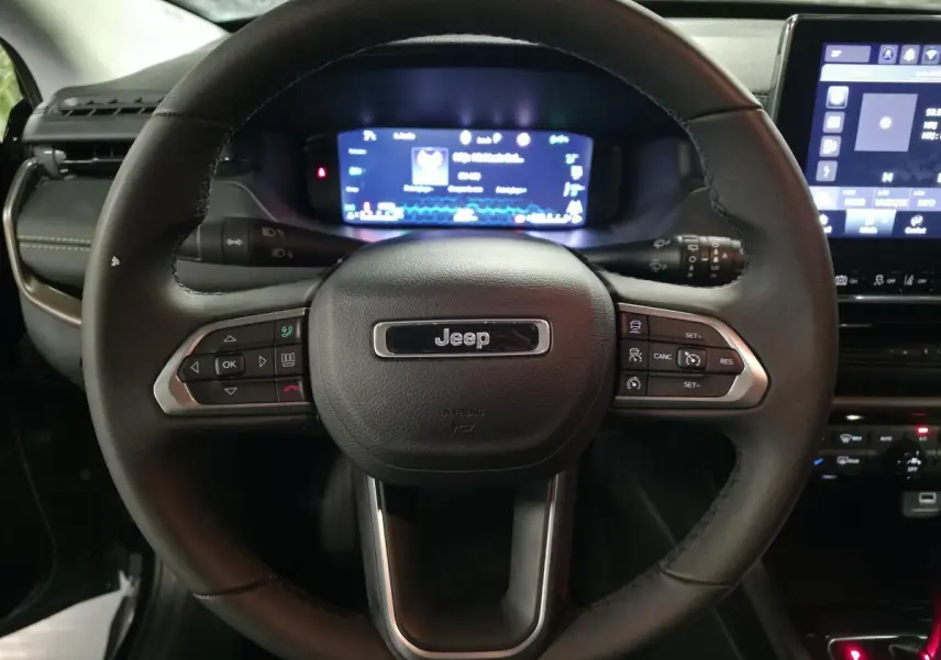 Volant cuir noir Jeep Compass 2024 vu de face avec commandes intégrées et tableau de bord numérique lumineux.