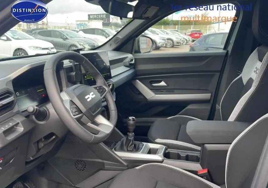 Vue intérieure côté conducteur du Dacia Duster 2026 vert cèdre, avec volant multifonction et boîte manuelle visible.