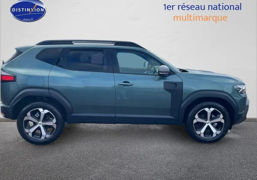 Profil droit du Dacia Duster 2026 vert cèdre avec barres de toit et jantes alliage visibles.