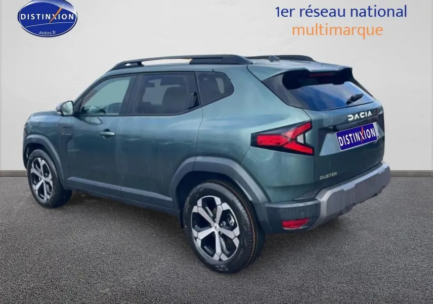 Vue 3/4 arrière droite du Dacia Duster vert cèdre avec barres de toit et jantes alliage visibles.
