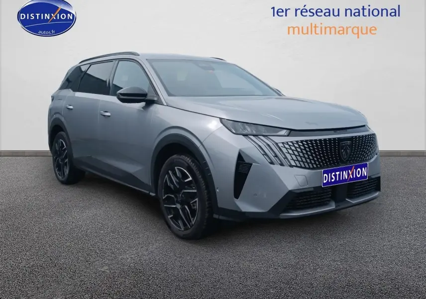 Peugeot 5008 gris artense en 3/4 avant droit, avec calandre distinctive et jantes alu noires.